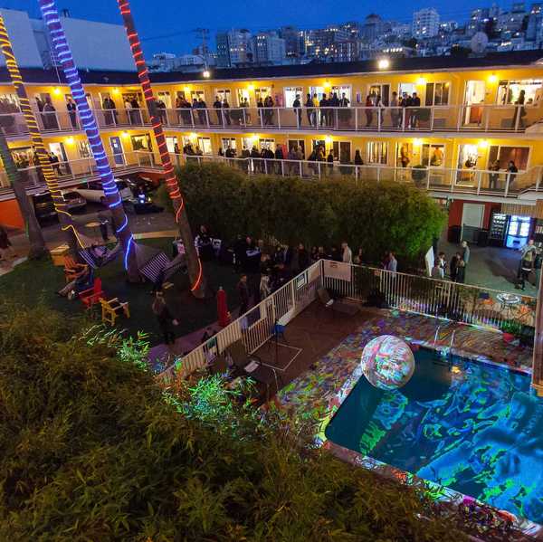 a motel around a pool lit up with art galleries in each room