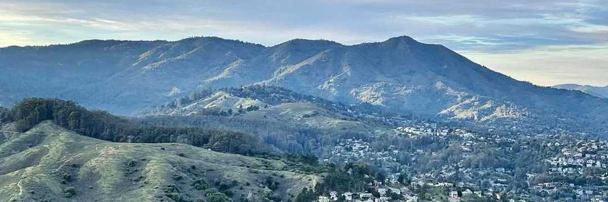 a mountain covered in blue and green with a town at the foot