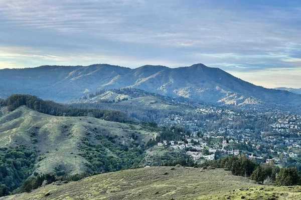 a mountain covered in blue and green with a town at the foot