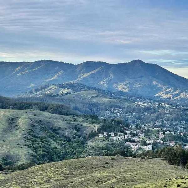 a mountain covered in blue and green with a town at the foot
