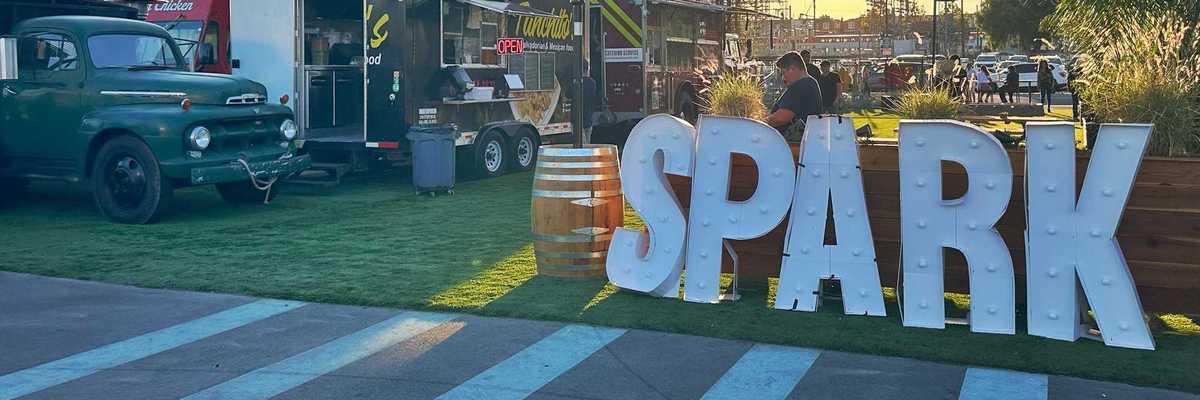 a park with the words SPARK in front and food trucks set up