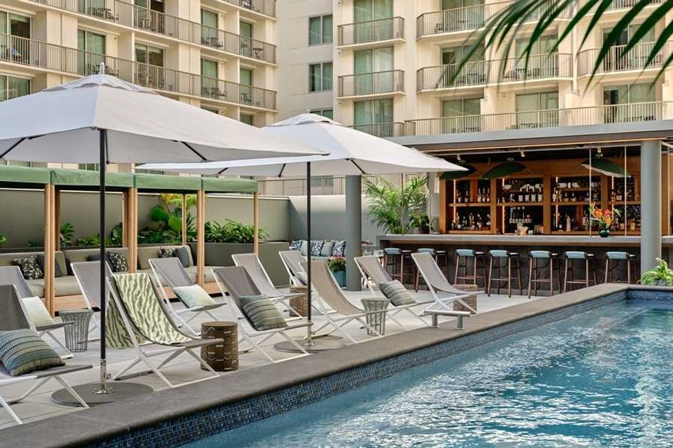 a pool with lounge chairs, umbrella, and a bar