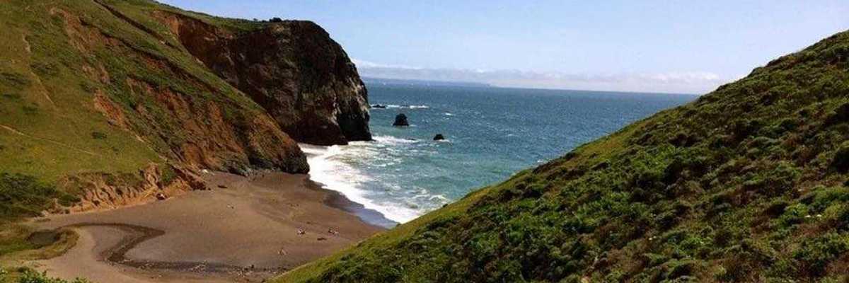 a secluded beach with a set of stairs leading down a hill