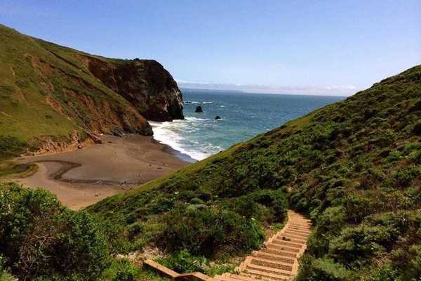 a secluded beach with a set of stairs leading down a hill