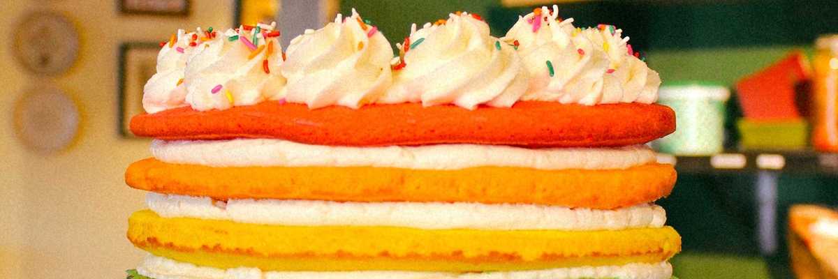 a seven layer cake in the colors of the rainbow with rainbow sprinkles on top