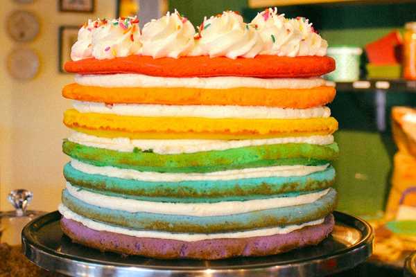 a seven layer cake in the colors of the rainbow with rainbow sprinkles on top