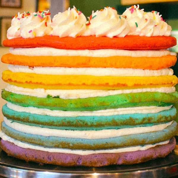 a seven layer cake in the colors of the rainbow with rainbow sprinkles on top