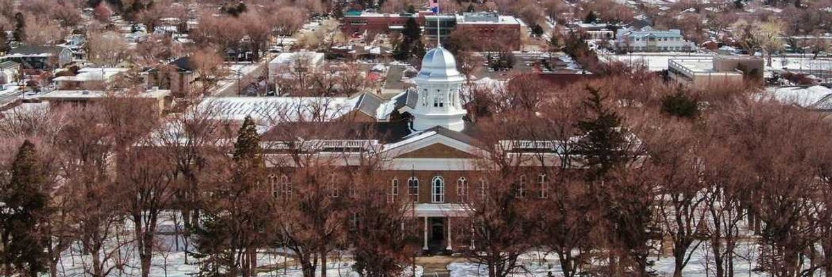 A snowy small town with a pretty capital building in front of mountains