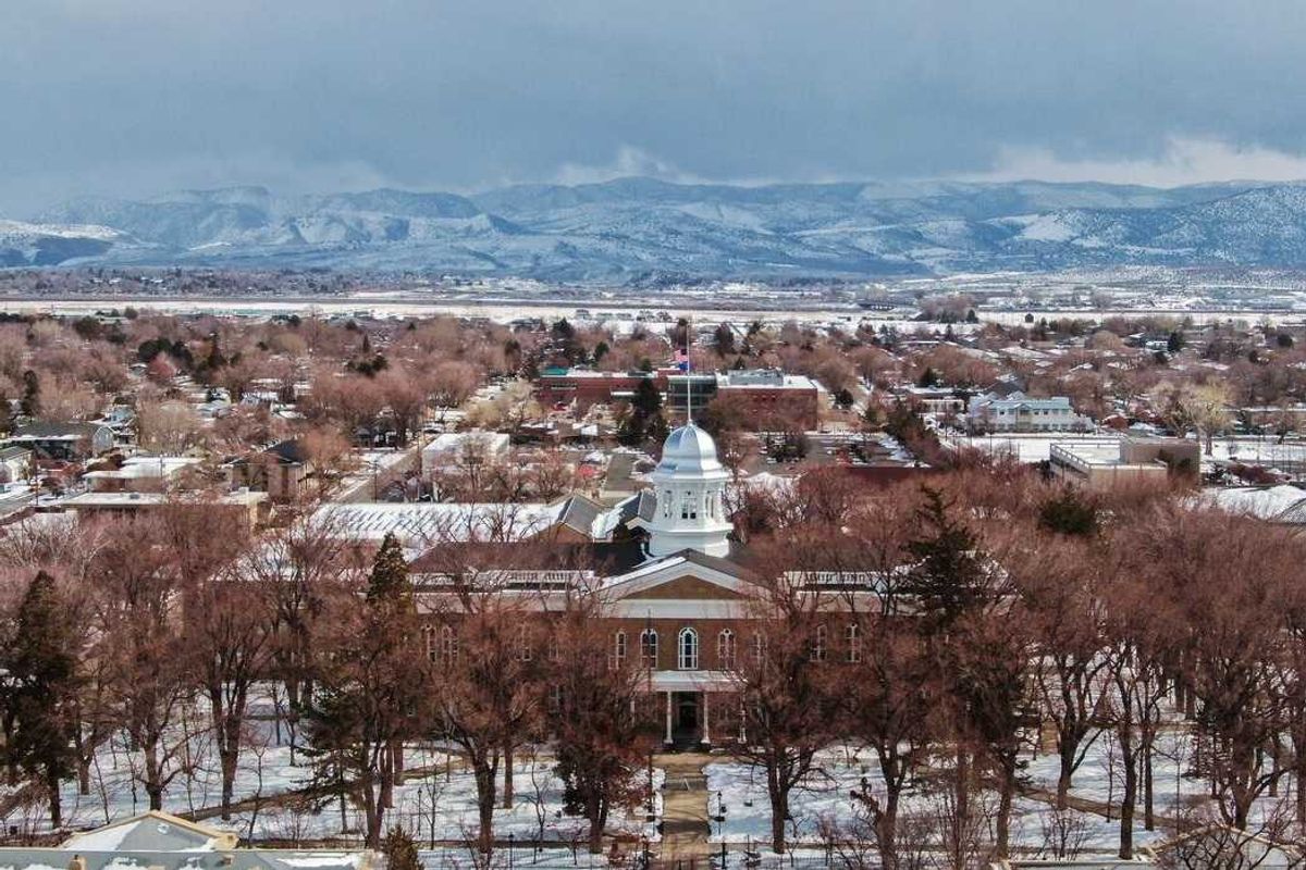 A snowy small town with a pretty capital building in front of mountains