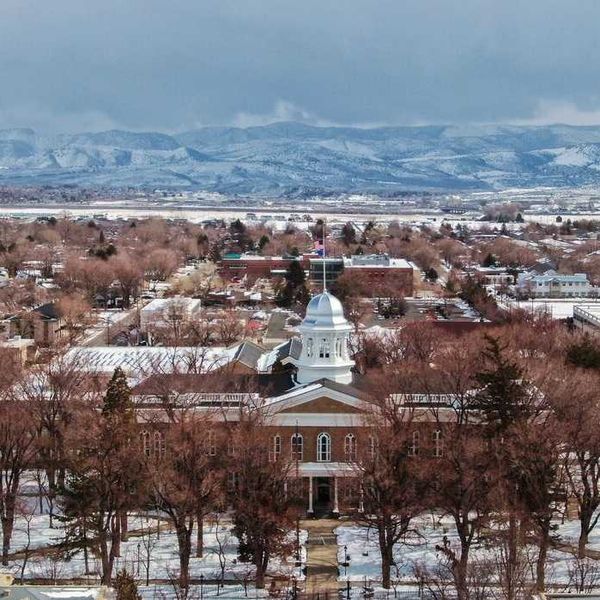 A snowy small town with a pretty capital building in front of mountains
