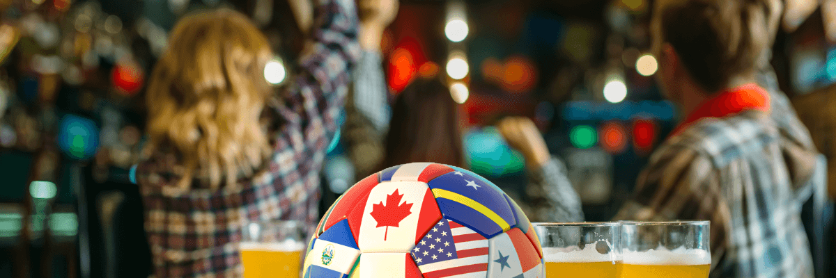 a soccer bar and pints of beer on a table with cheering fans in a bar behind