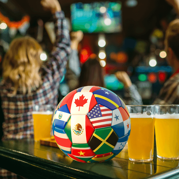 a soccer bar and pints of beer on a table with cheering fans in a bar behind