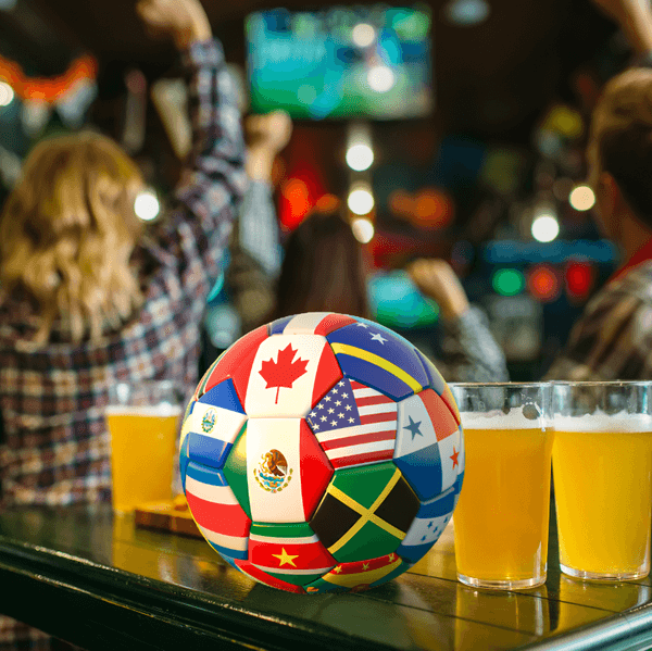 a soccer bar and pints of beer on a table with cheering fans in a bar behind