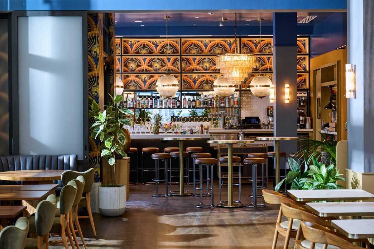 a stylish restaurant with blue walls and a large bar with peacock wallpaper