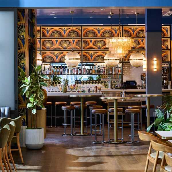 a stylish restaurant with blue walls and a large bar with peacock wallpaper