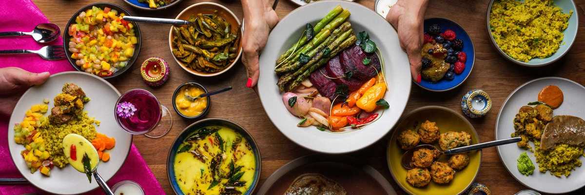 a table full of plates and dishes of colorful Indian food