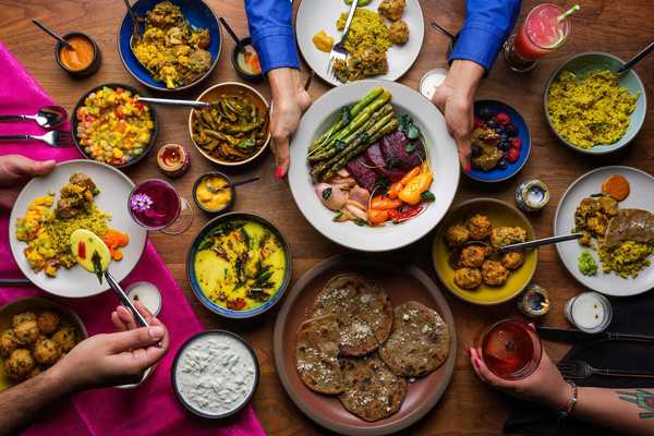 a table full of plates and dishes of colorful Indian food