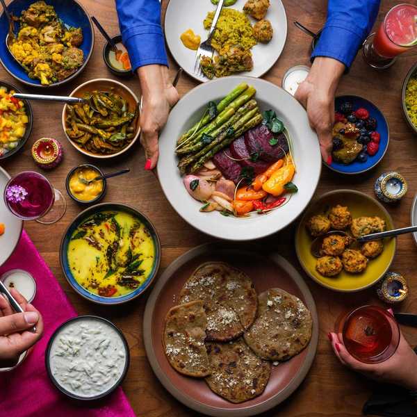 a table full of plates and dishes of colorful Indian food