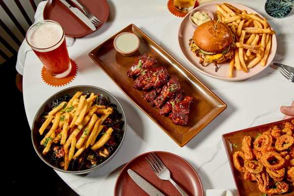 a table of food including bbq ribs, a burger and fries, mussels and fries, and calamari