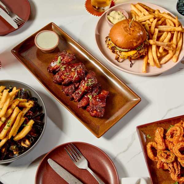 a table of food including bbq ribs, a burger and fries, mussels and fries, and calamari