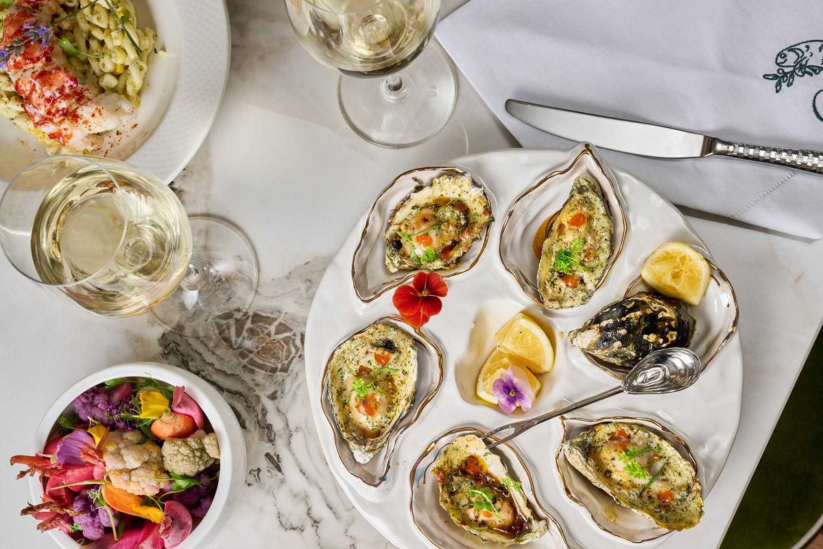 A table spread with beautiful grilled oysters and pickled veggies and wine