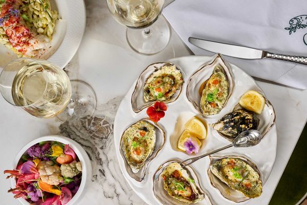 A table spread with beautiful grilled oysters and pickled veggies and wine