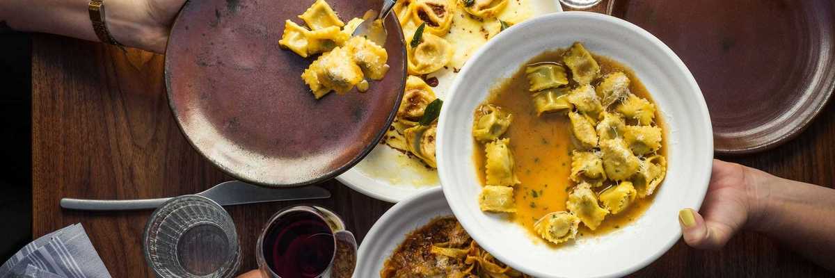 a table with someone spooning agnolotti pasta