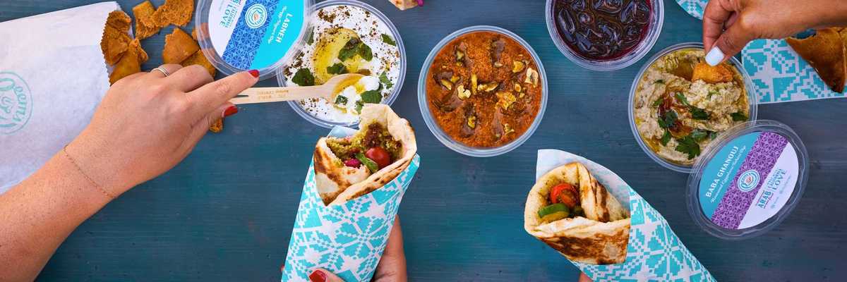 a tablescape with Middle Eastern wraps in blue paper and dips