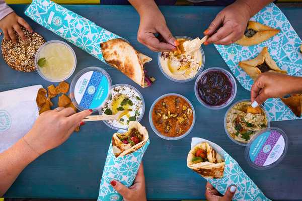 a tablescape with Middle Eastern wraps in blue paper and dips