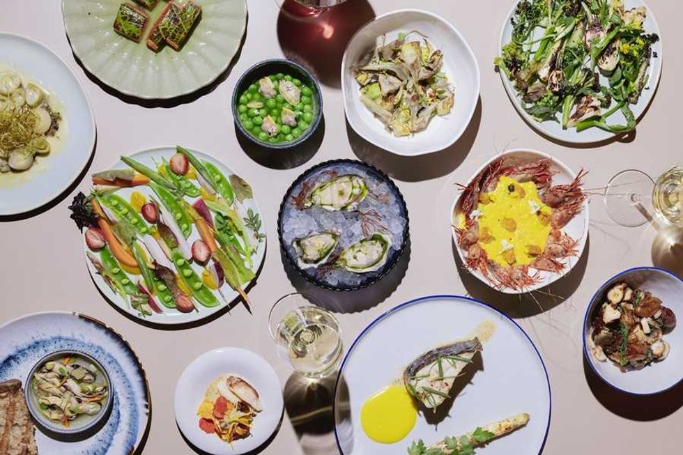 A variety of gourmet dishes artfully arranged on a table with wine glasses.