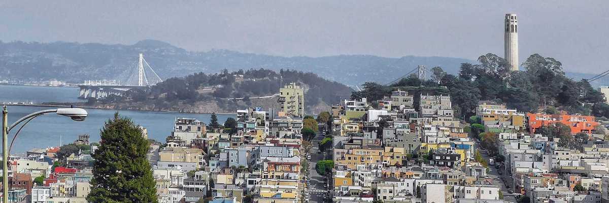 a view of san francisco with coit tower on telegraph hill on one side and the bay on the other