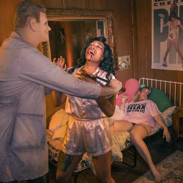 a woman being murdered by a man in a mask with another dead girl on a bed