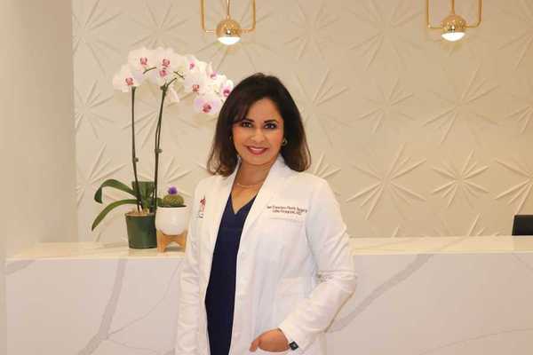 a woman doctor in a white lab coat standing in front of an orchid