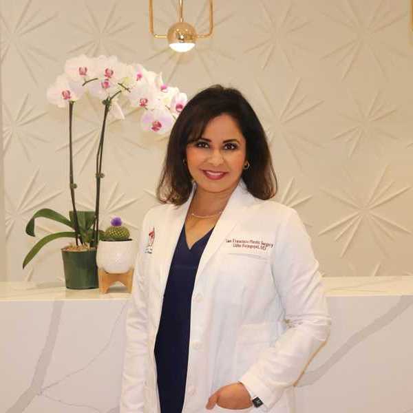 a woman doctor in a white lab coat standing in front of an orchid