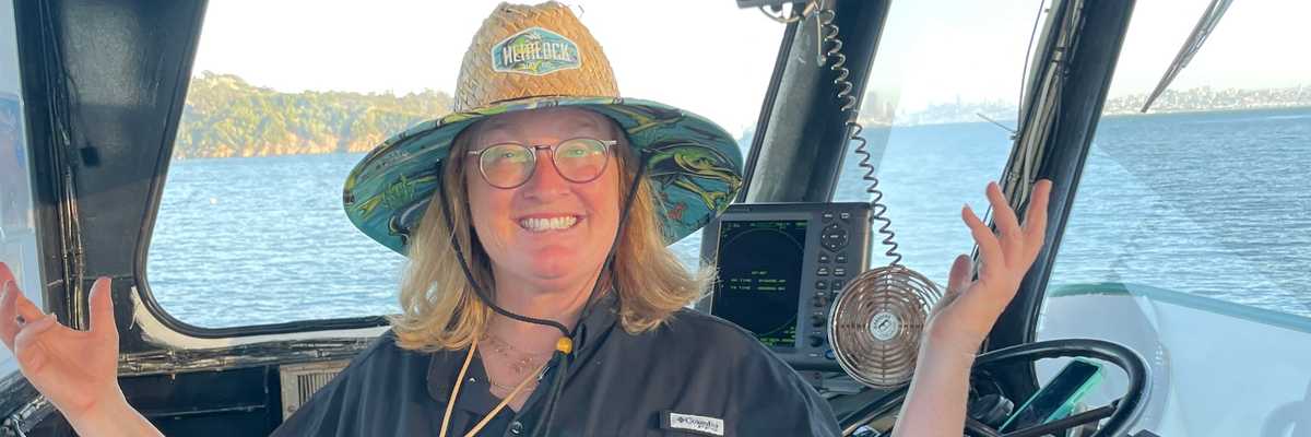 a woman in a straw hat standing in the captain's cabin of a boat