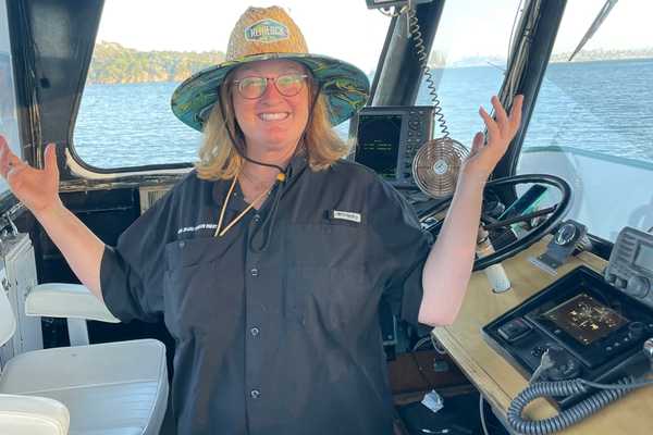 a woman in a straw hat standing in the captain's cabin of a boat