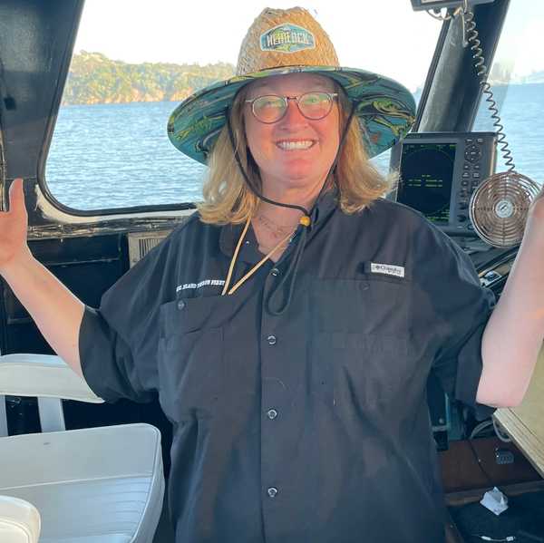 a woman in a straw hat standing in the captain's cabin of a boat