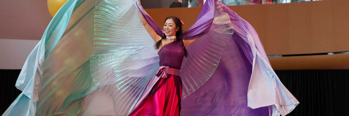 a woman in flowy colorful clothing on a stage dancing