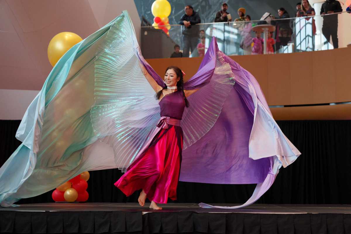 a woman in flowy colorful clothing on a stage dancing