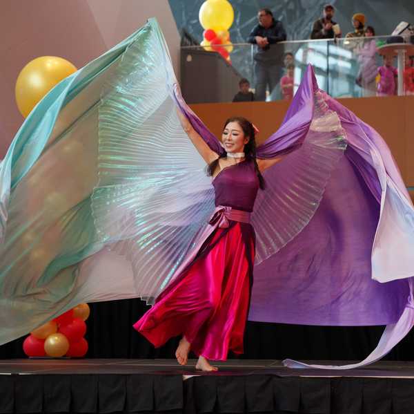 a woman in flowy colorful clothing on a stage dancing