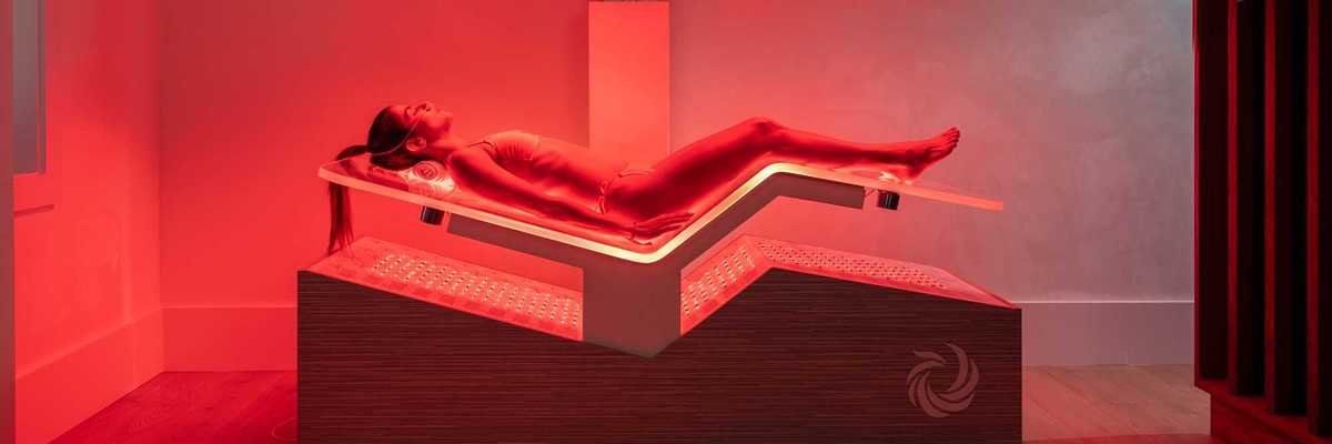 a woman laying in a high tech Ammortal Chamber with red light all around