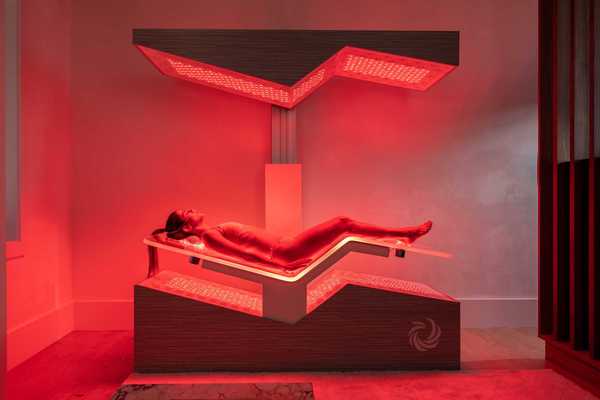 a woman laying in a high tech Ammortal Chamber with red light all around