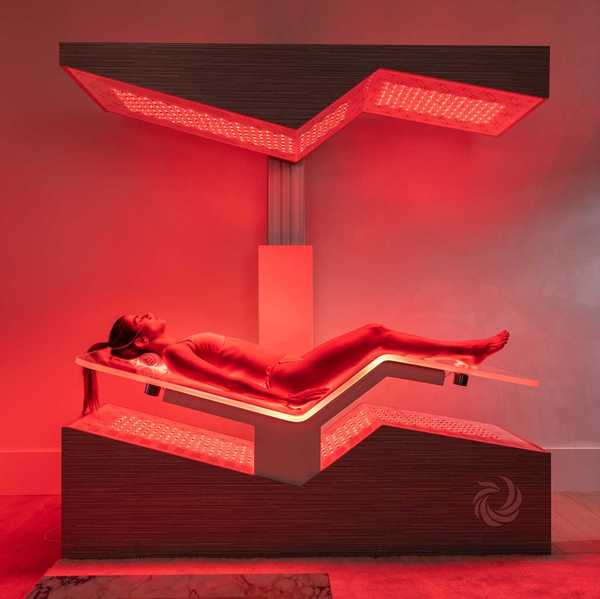 a woman laying in a high tech Ammortal Chamber with red light all around