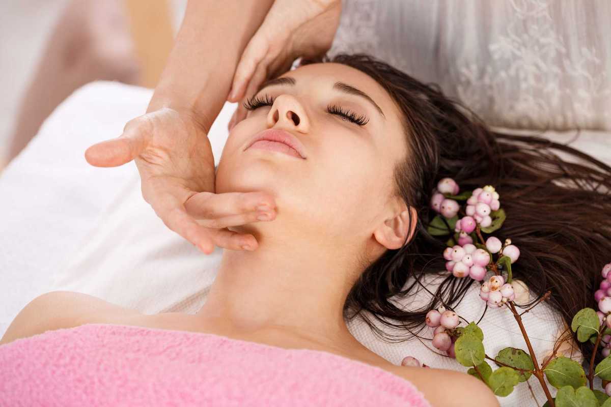 a woman laying on a treatment bed getting a facial with a sprig of berries next to her