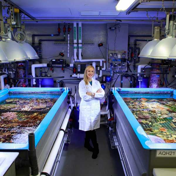 a woman standing in a lab with coral in tanks