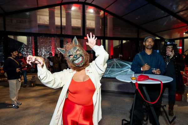 a woman wearing a wolf mask and a red outfit and white jacket at a party