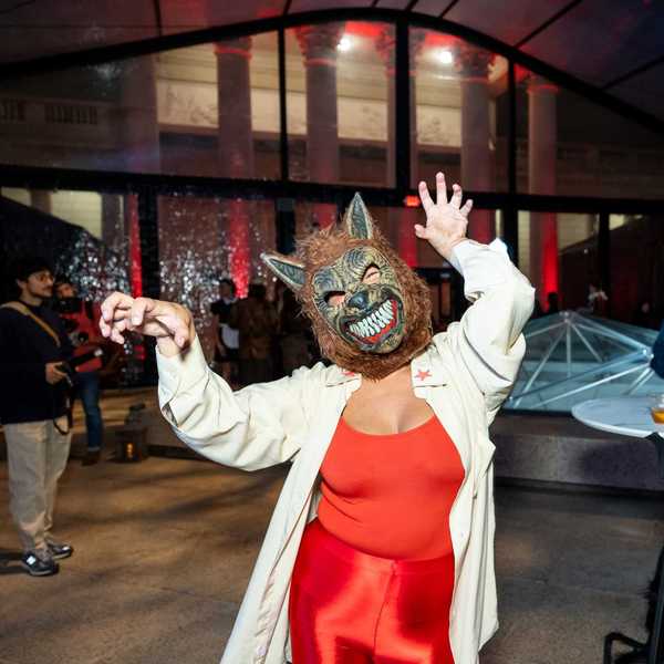 a woman wearing a wolf mask and a red outfit and white jacket at a party
