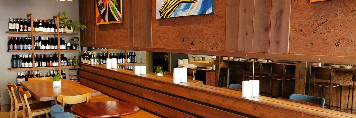 a wood paneled dining room with small round tables and a wall of wine bottles