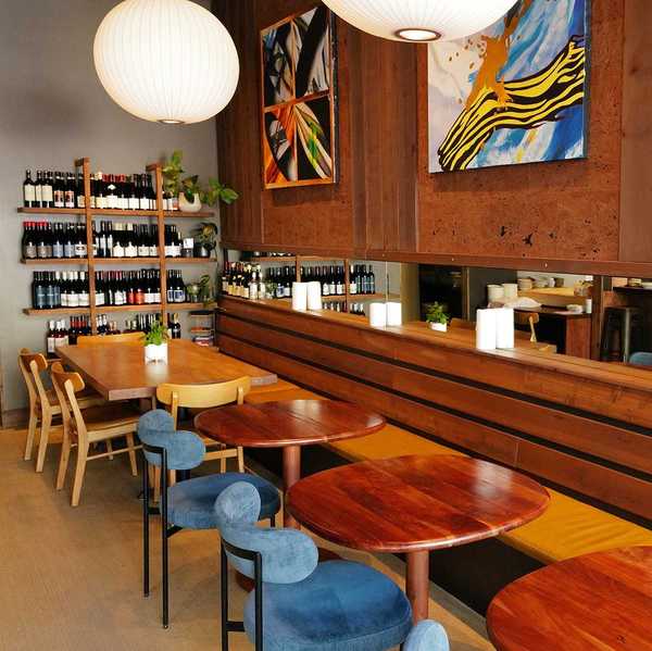 a wood paneled dining room with small round tables and a wall of wine bottles