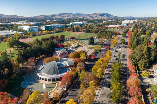 Aerial view of a campus with fall foliage and distant hills.